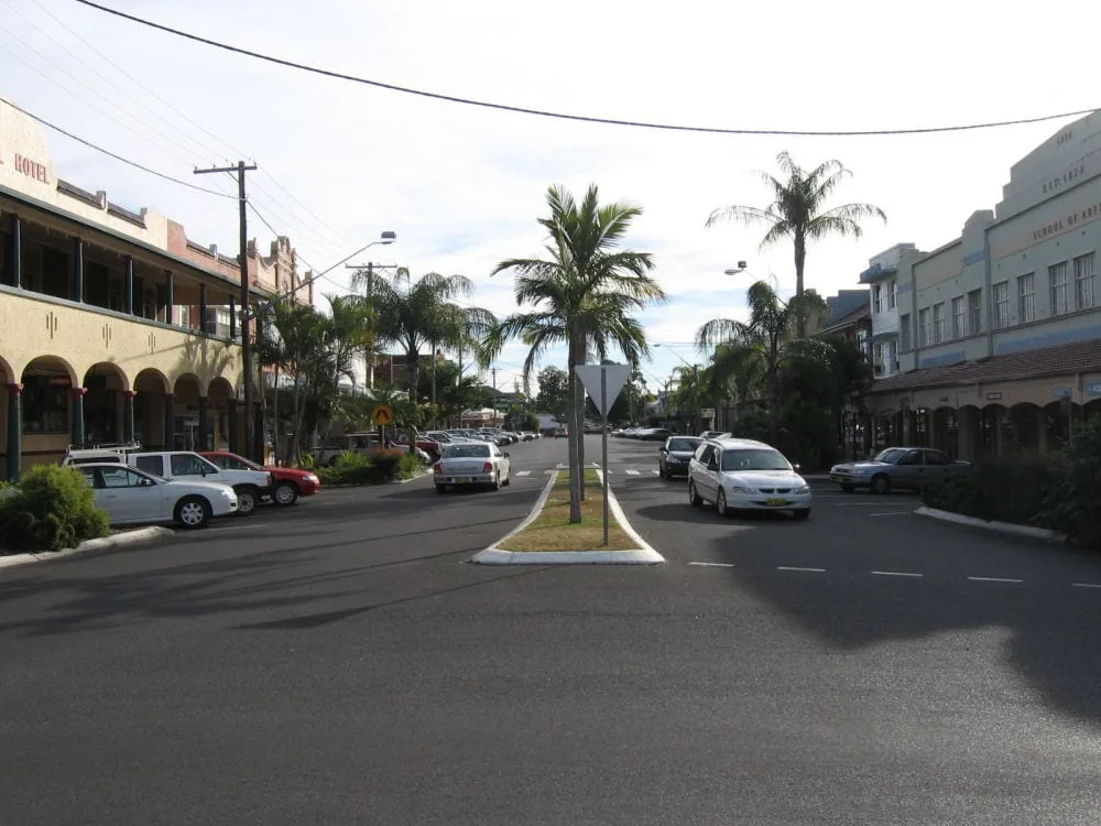 A wide street lined with historic commercial buildings, palm trees, and parked cars
