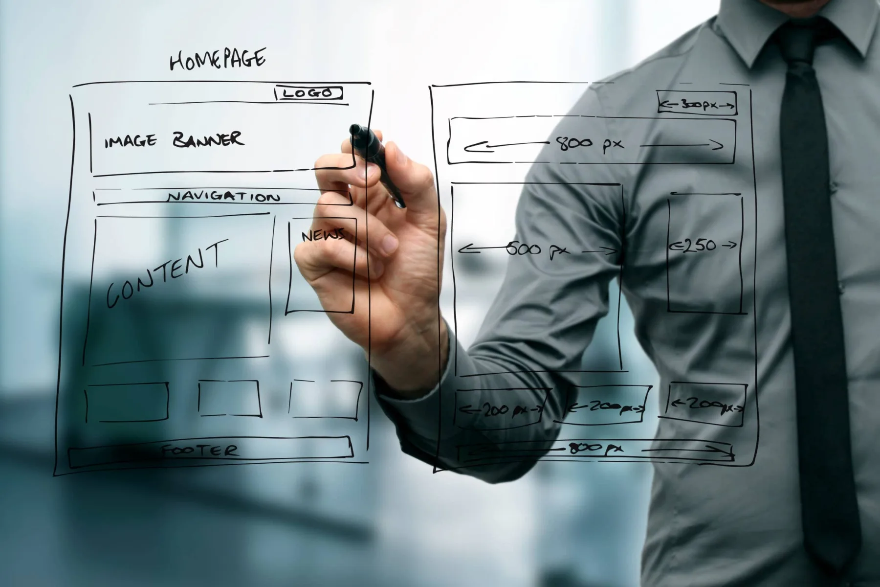 A man in a grey dress shirt and tie uses a black marker to sketch a website wireframe onto a transparent glass pane.