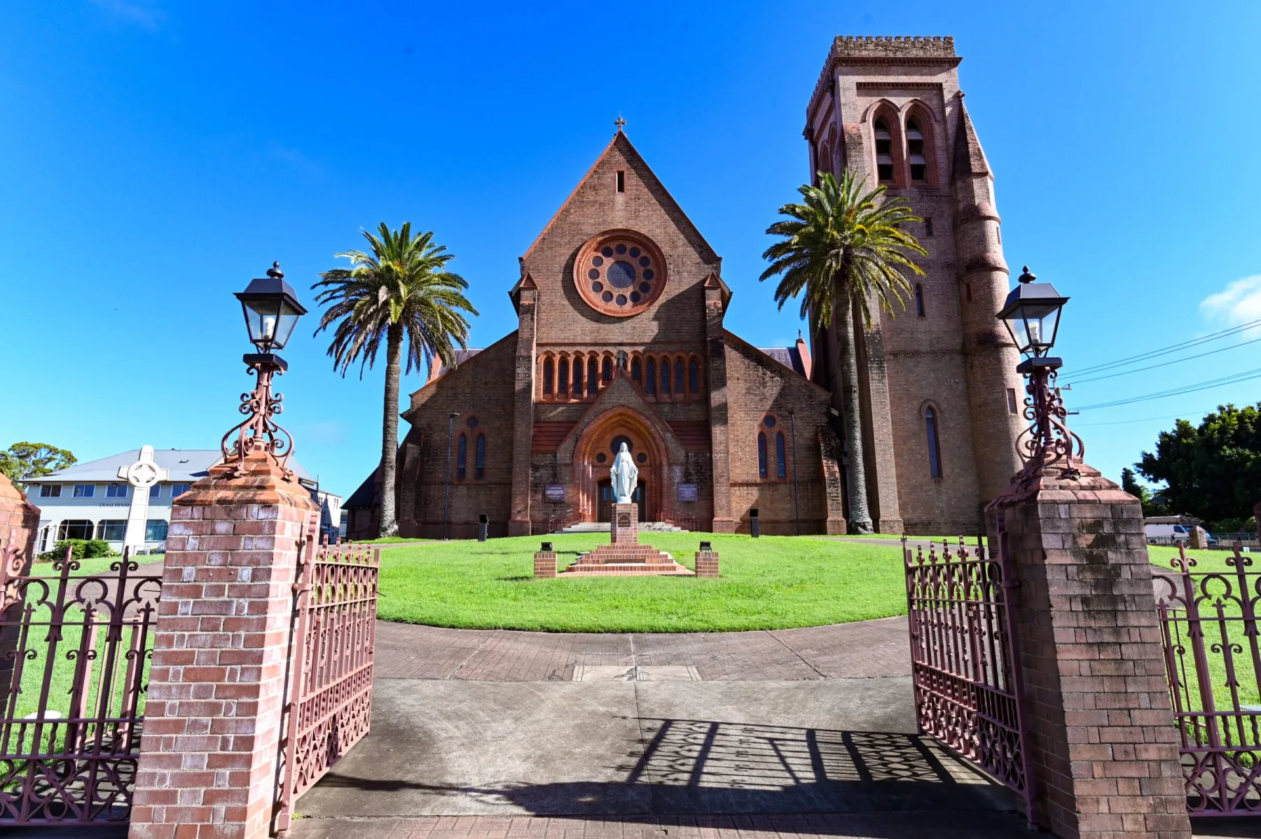 A wide shot of a historic brick church with a tall bell tower under a clear blue sky.