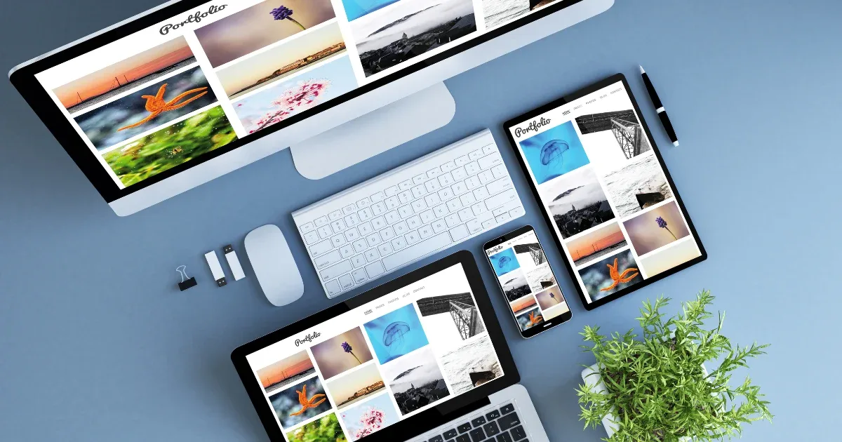 An overhead shot of a desktop monitor, laptop, tablet, and smartphone arranged on a light blue desk demonstrates responsive web design.