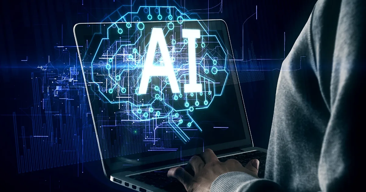 A side-view shot shows a person in a grey hoodie using a laptop, with a glowing blue digital overlay emanating from the screen.