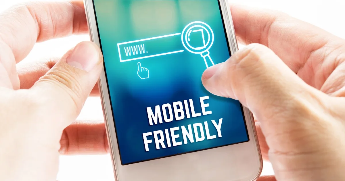 A close-up shot shows a person's hands holding a smartphone that displays a teal screen with the bold text 'MOBILE FRIENDLY.