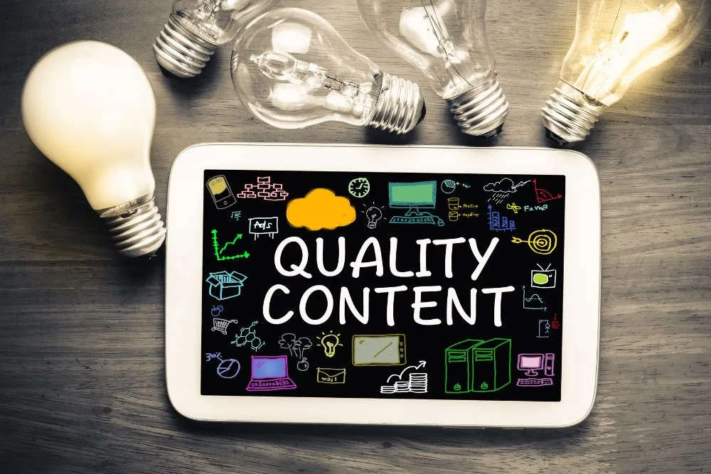 An overhead shot of a white tablet lying on a wooden surface, displaying the phrase "QUALITY CONTENT" in bold white letters.