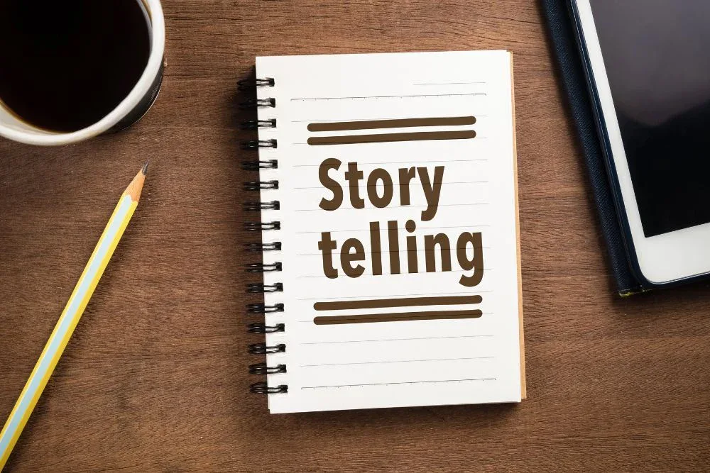 An overhead shot of a spiral notebook on a wooden desk with the word "Storytelling" printed on its lined page.