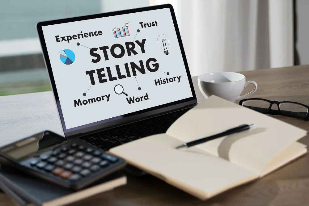A laptop sits on a wooden desk displaying a "STORY TELLING" infographic on its screen