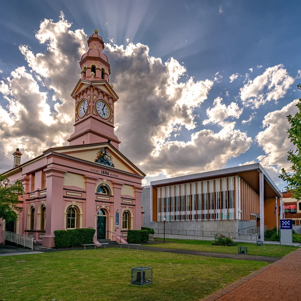 A low-angle shot of the historic Bundaberg Court House, a grand pink building with a tall clock tower, built in 1886.