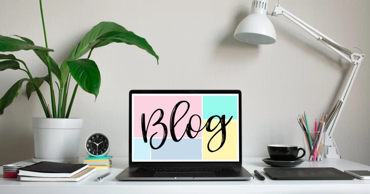 A cosy, minimalist workspace featuring a laptop with the word 'Blog' in cursive on a pastel-coloured background.