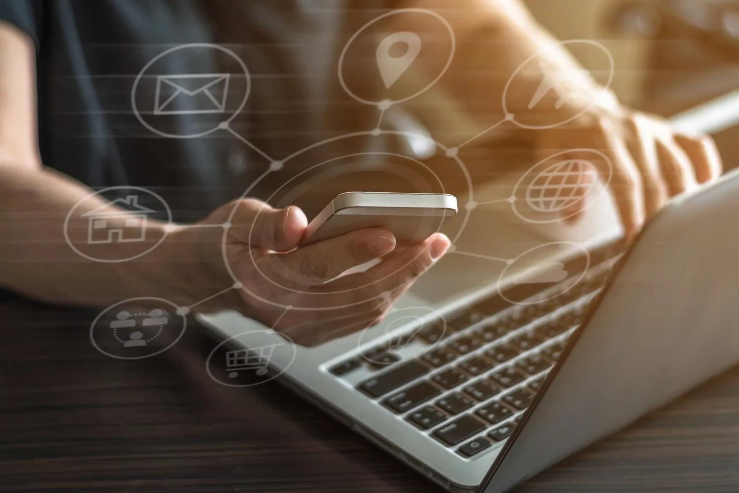 hands holding a phone and a laptop