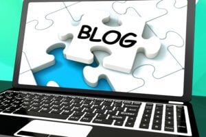 Laptop screen showing a puzzle piece with the word "BLOG" fitting into a business website strategy concept.
